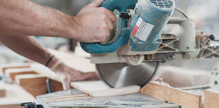 Employers Liability Insurance: A person operating a power saw on a peice of wood. 